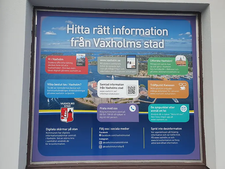 Fönster med dekal som ger information om Vaxholms stads kommunikationskanaler.