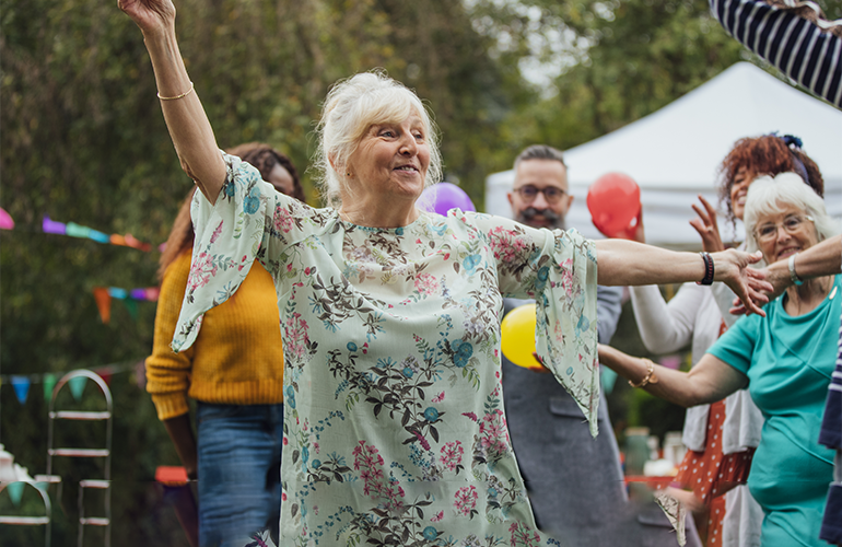 Bilden visar äldre personer som dansar på en festival.