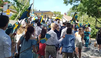 Parad av skolbarn med flaggor fotade bakifrån.