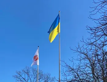 Ukrainaflagga på stång med en Vaxholmsflagga i bakgrunden.